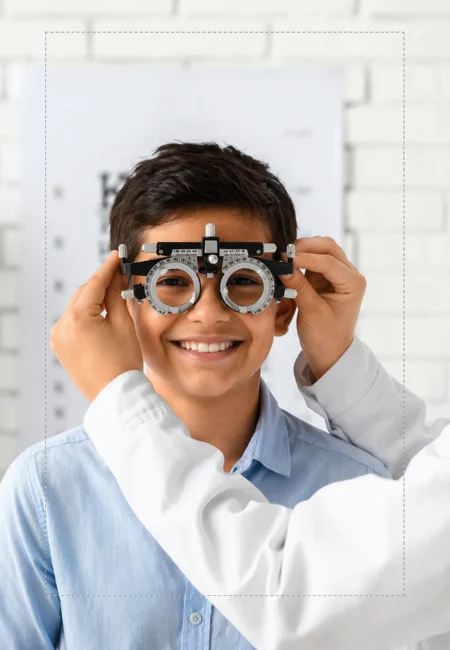 Menino ajustando uma armação de testes durante o exame de refração